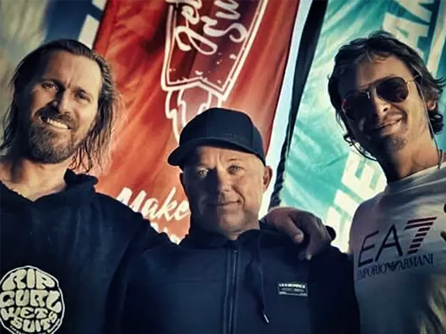 Wayne, Andreas and Rafa standing next to each other in front of Jet Surfing Nation flags.