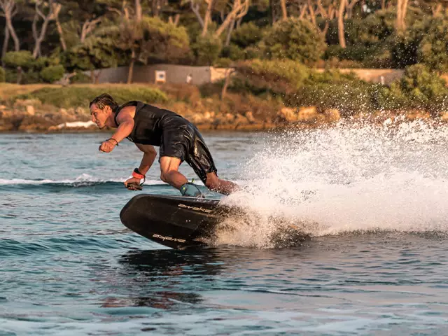 A man riding an Awake Ravic S electric surfboard at the La Reserva watersports lagoon.
